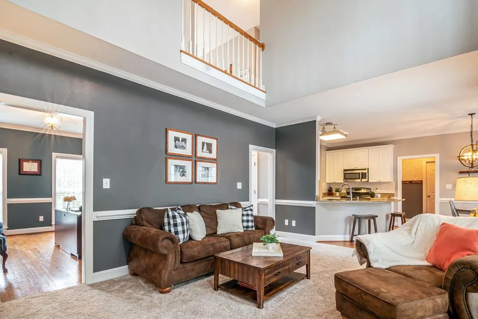 Living room with a dark charcoal accent wall, brown leather sofa, and open sightline to the kitchen